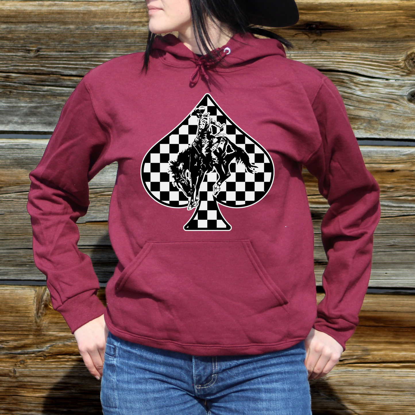 woman wearing maroon hoodie with black and white checkered spade design with bucking horse in the middle