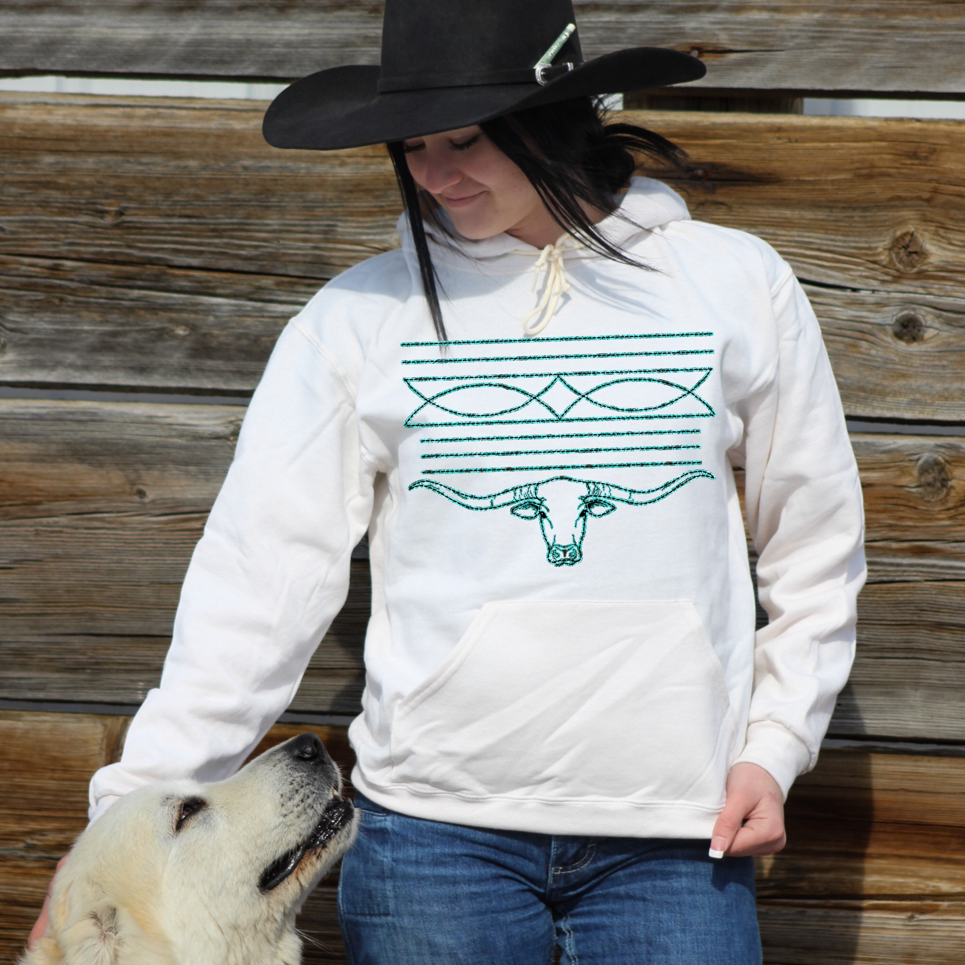 woman wearing cream colored hoodie with turquoise bootstitch design with a longhorn.